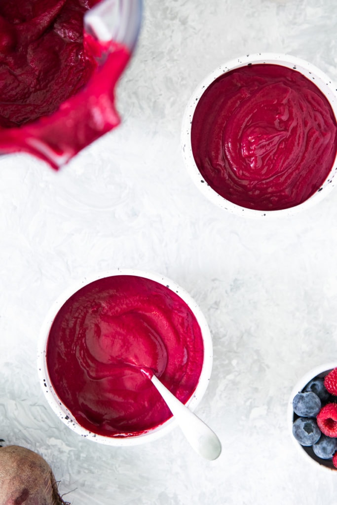 Two bowls of Cinnamon Berry Beet Smoothie freshly poured with the blender and a bowl of mixed berries sitting beside.