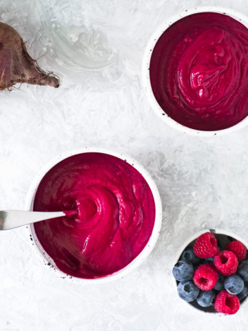 Two bowls of Cinnamon Berry Beet Smoothie freshly poured with the blender and a bowl of mixed berries sitting beside.