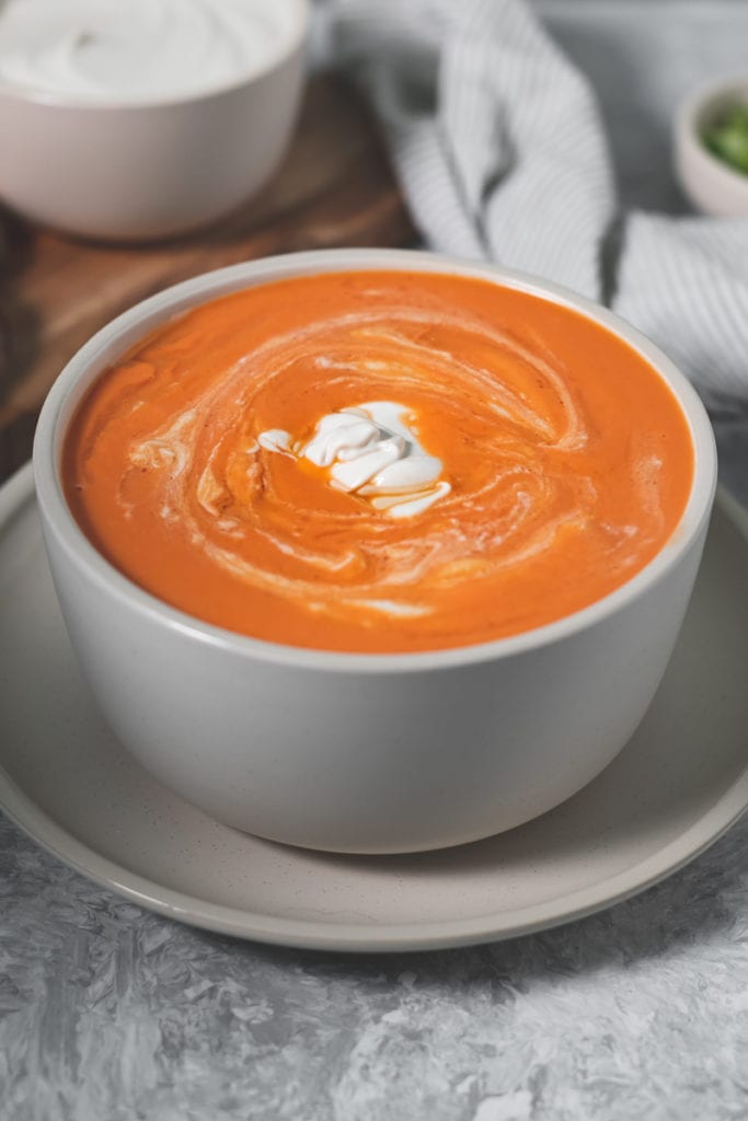 A heaping bowl of tomato soup topped with a dollop of cashew yogurt.