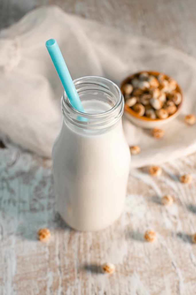 A bottle of tigernut milk in the middle of spilled tigurnuts.