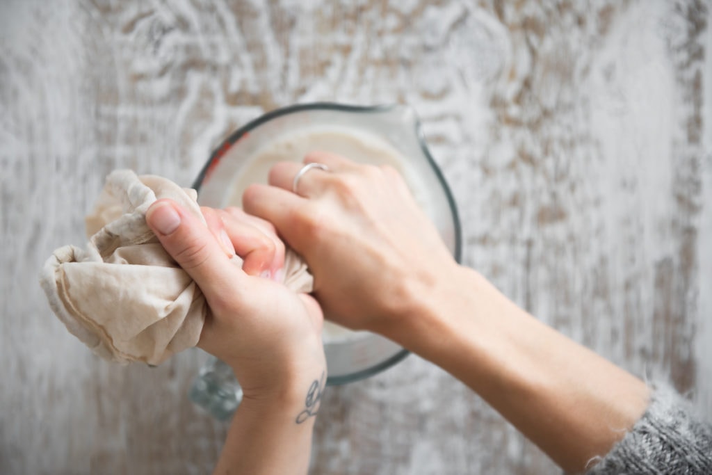 Tigernut Milk being squeezed through a plant milk bag.