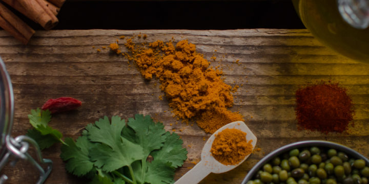 A table of whole food ingredients including mung beans, goji berries, turmeric, cinnamon stick herbs and oil.