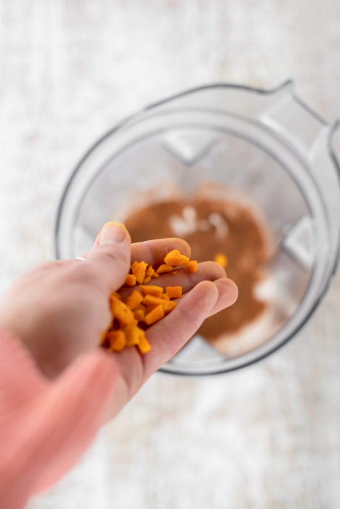 Chopped turmeric being added into a blender jug.