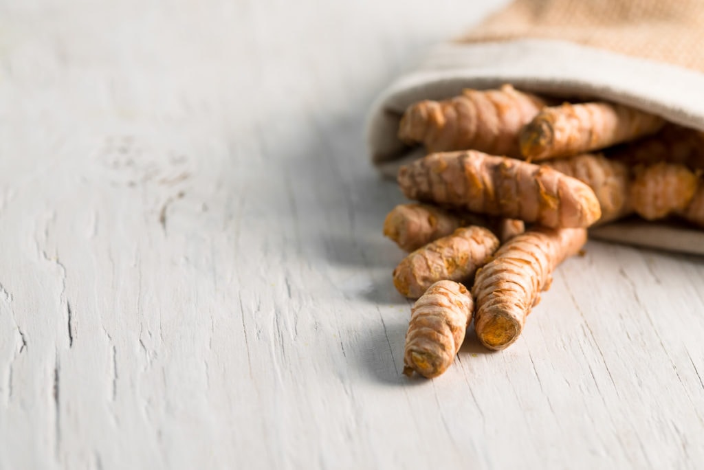 A burlap bag with turmeric tubers spilling out.