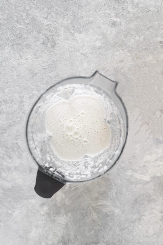 Frothy, freshly blended coconut milk still in the blender jug. 