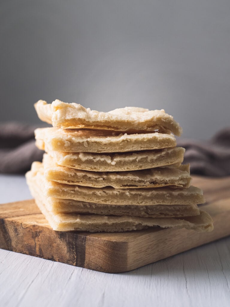 Homemade flatbread stacked on a wooden block with a linen cloth in the background.