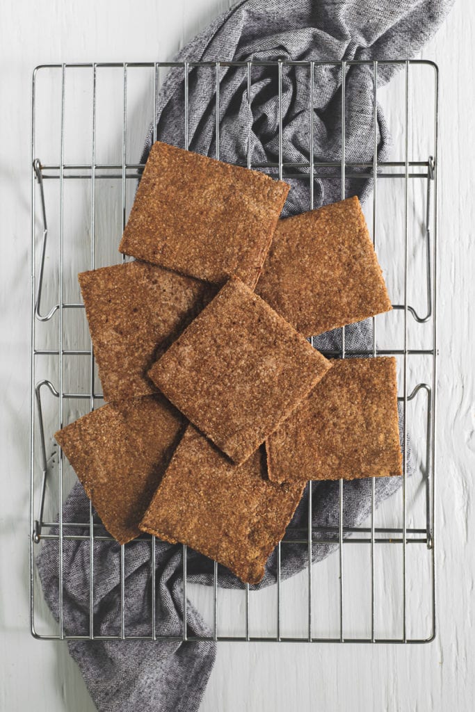 Graham Crackers laying flat on a cooling wrack, sitting on top of a bunched up linen cloth