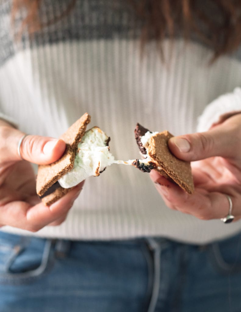 An ooey gooey s'more being broken apart. 