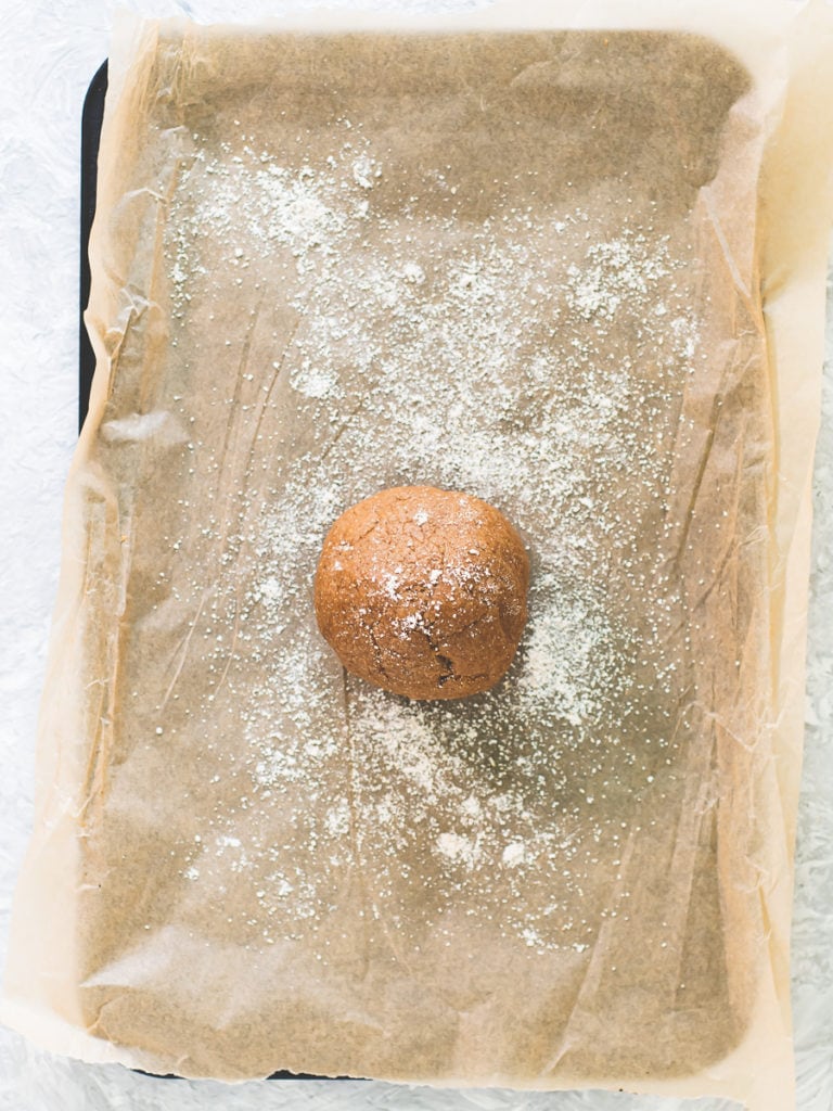 A ball of Graham Cracker dough placed on a baking sheet and sprinkled with flour.