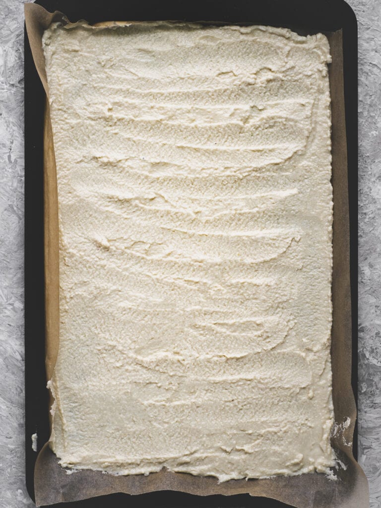 Flatbread batter spread roughly on a parchment lined baking sheet.