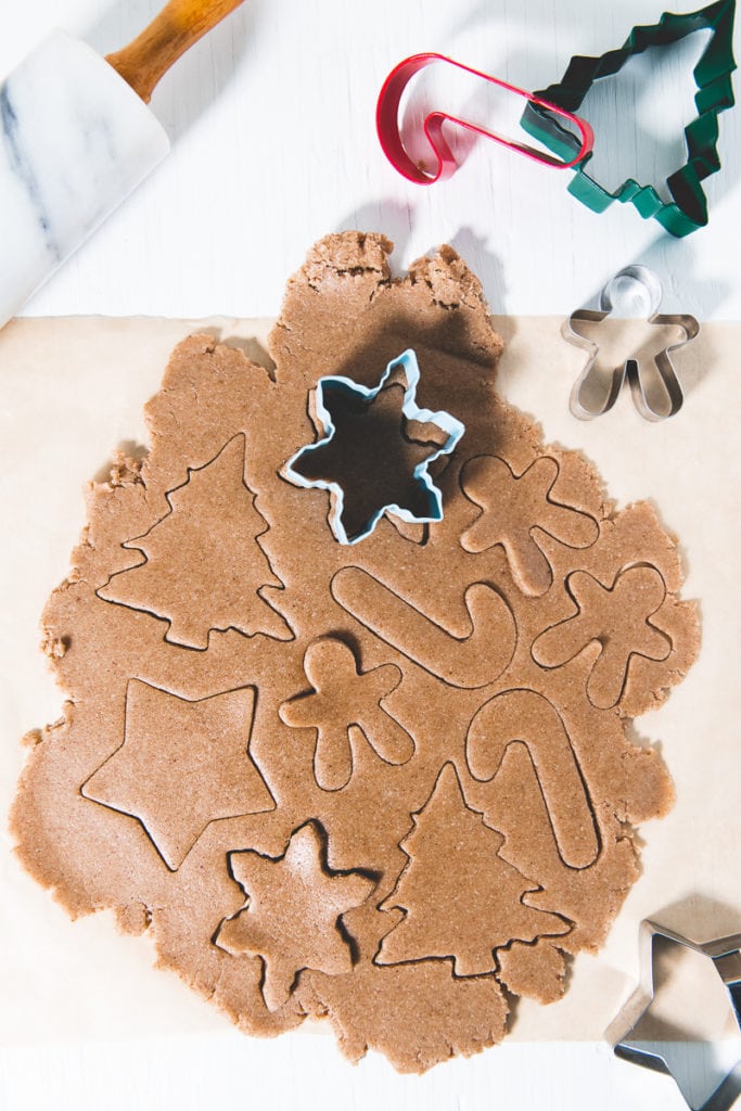 Gingerbread cookie dough rolled out and scored with holiday themed cookie cutters.