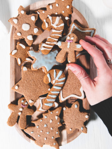 A gingerbread cookie being picked up from a full plate.