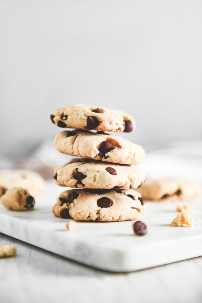 A stack of almond flour chocolate chip cookies surrounded by crumbs.