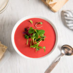 Vibrantly coloured vegan beet soup, garnished with fresh sprouts.