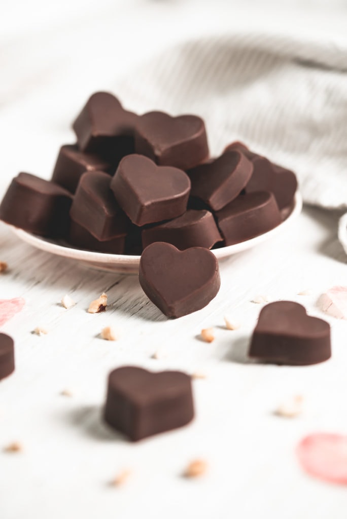 An overflowing plate of heart-shaped chocolate hazelnut truffles.