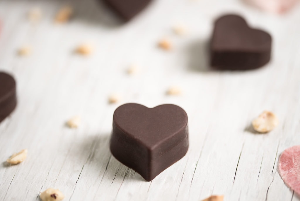 A heart-shaped chocolate surrounded by hazelnut crumbs and more heart shaped chocolates.