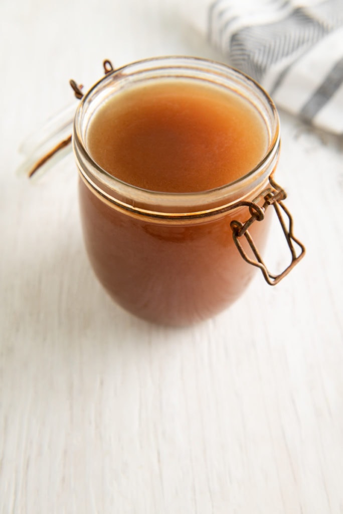 A full jar of vibrant and rich homemade vegetable broth.