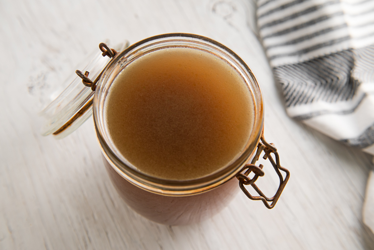 A latch-jar filled with a rich-coloured, homemade vegetable broth.