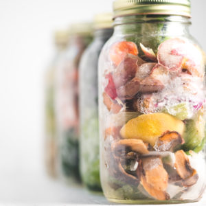 A row of jars filled with frozen vegetables scraps.