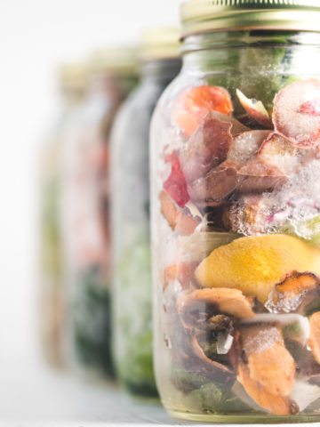 A row of jars filled with frozen vegetables scraps.