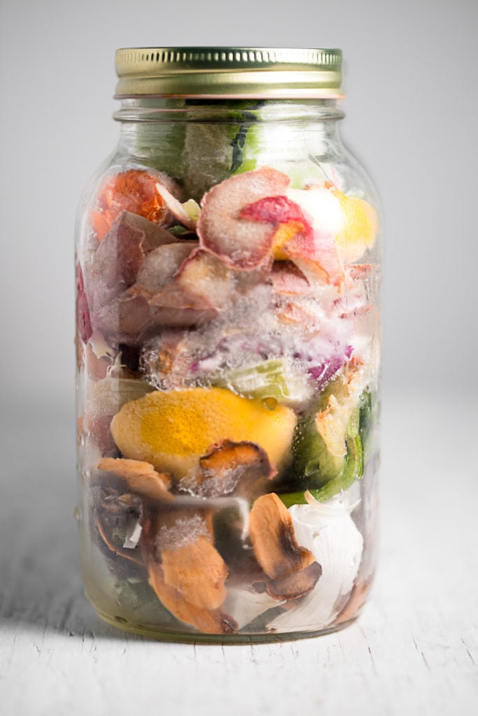 A mason jar filled with frozen vegetables scraps.
