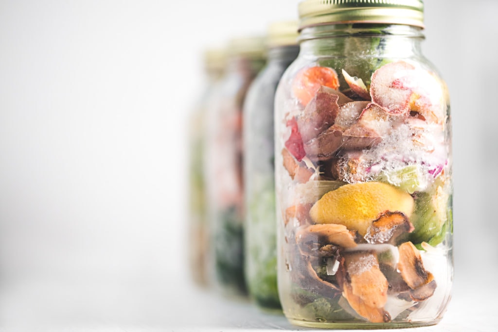A row of jars filled with frozen vegetables scraps.