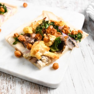 A slice of homemade flatbread pizza loaded with roasted chickpeas, cauliflower and kale.