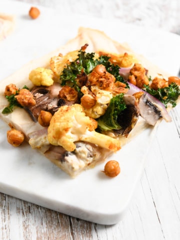 A slice of homemade flatbread pizza loaded with roasted chickpeas, cauliflower and kale.