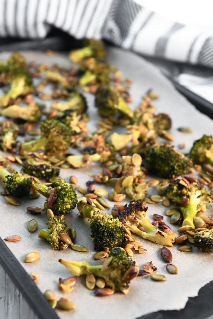 A sheet pan full of roasted broccoli and pumpkin seeds.