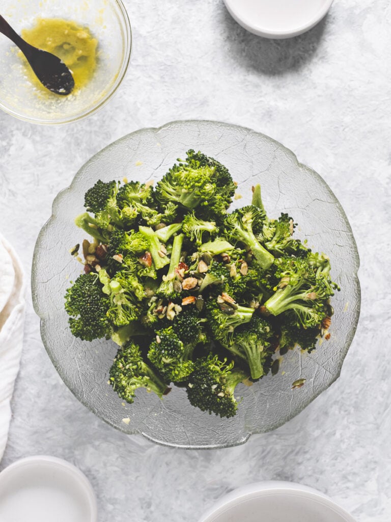 A bowl of fresh broccoli florets, chopped almonds and pumpkin seeds freshly tossed in a lemon garlic sauce.