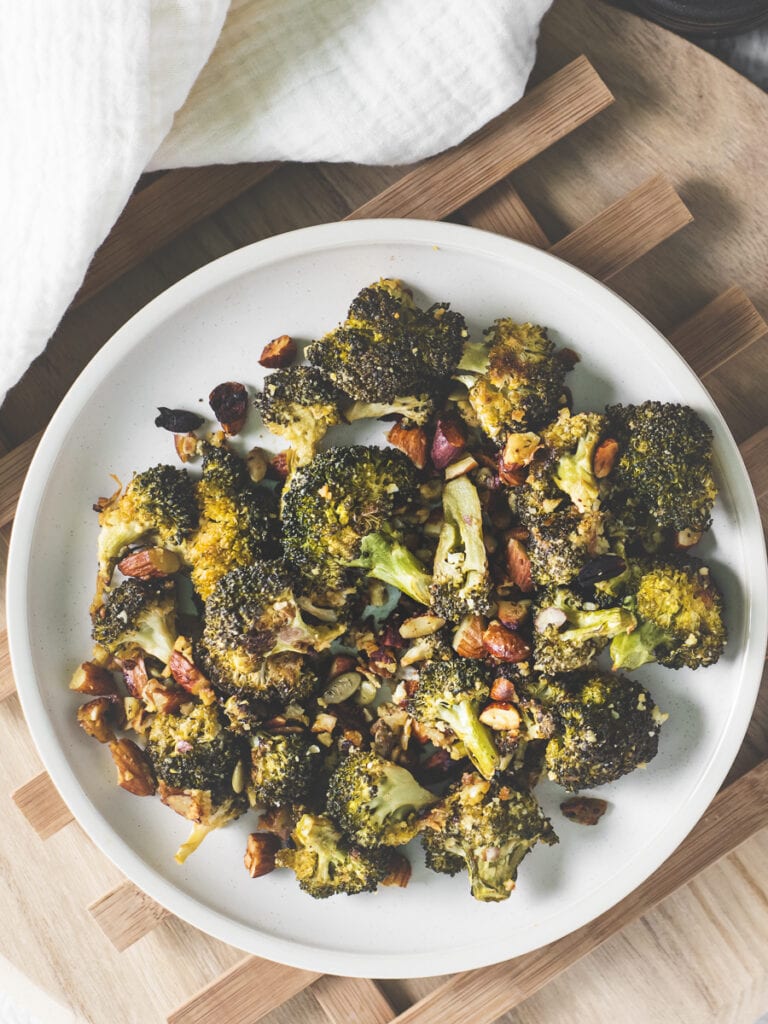 A plate of roasted broccoli, almonds and pumpkin seeds.