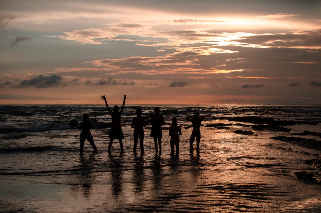 Silhouettes of a group of women enjoying and embracing a beautiful sunset on a beach.