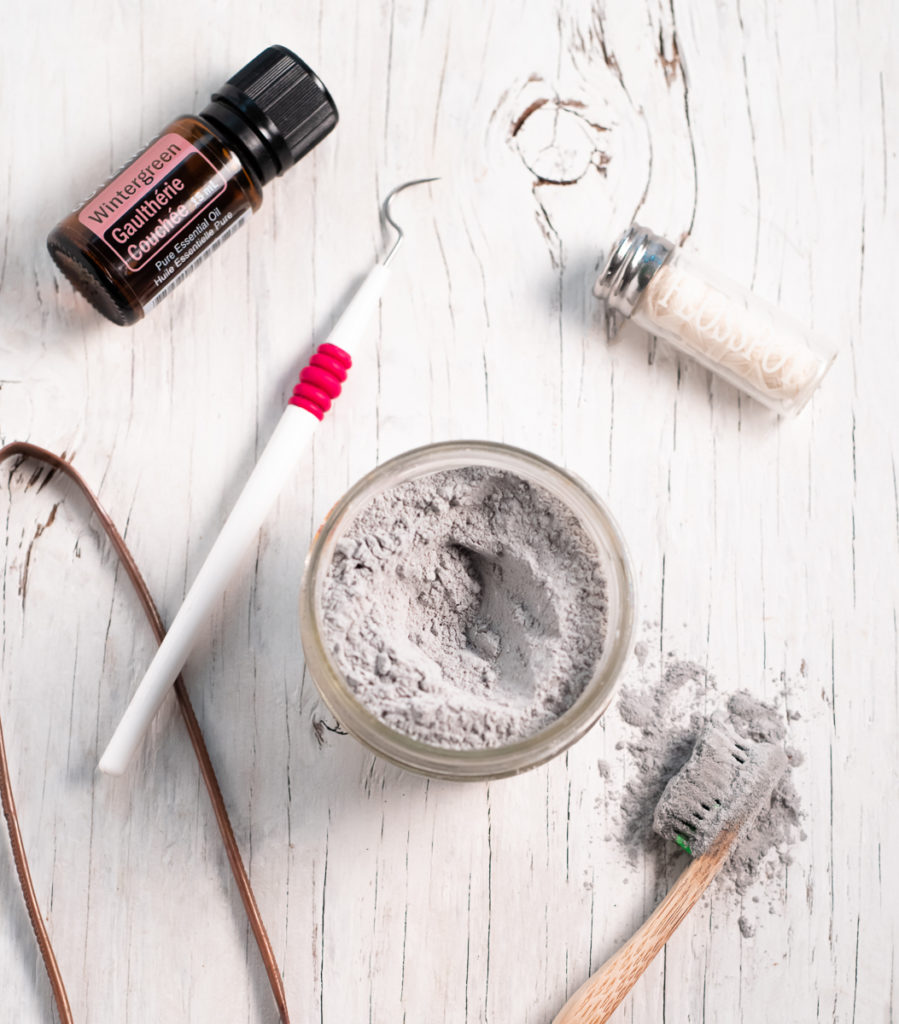 Homemade Charcoal toothpowder surrounded by oral care items.