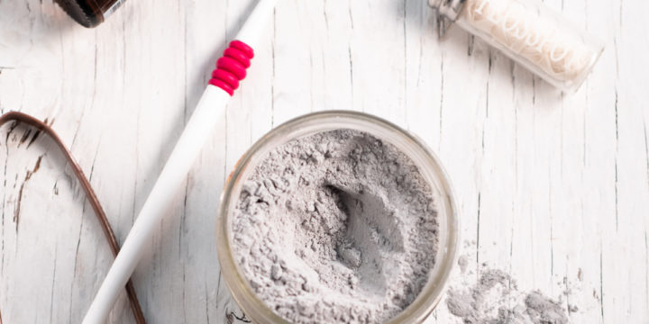 Homemade Charcoal toothpowder surrounded by oral care items.