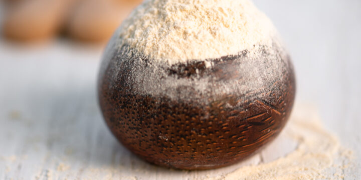 A bowl of powdered sugar with cookies in the background.A bowl of powdered sugar with cookies in the background.