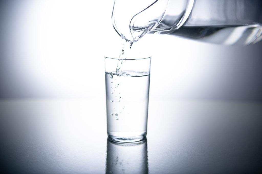 Water being poured out of a pitcher into a drinking glass.