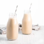 Two small milk jars filled with vanilla spice smoothies and a grey and white straw placed in each.