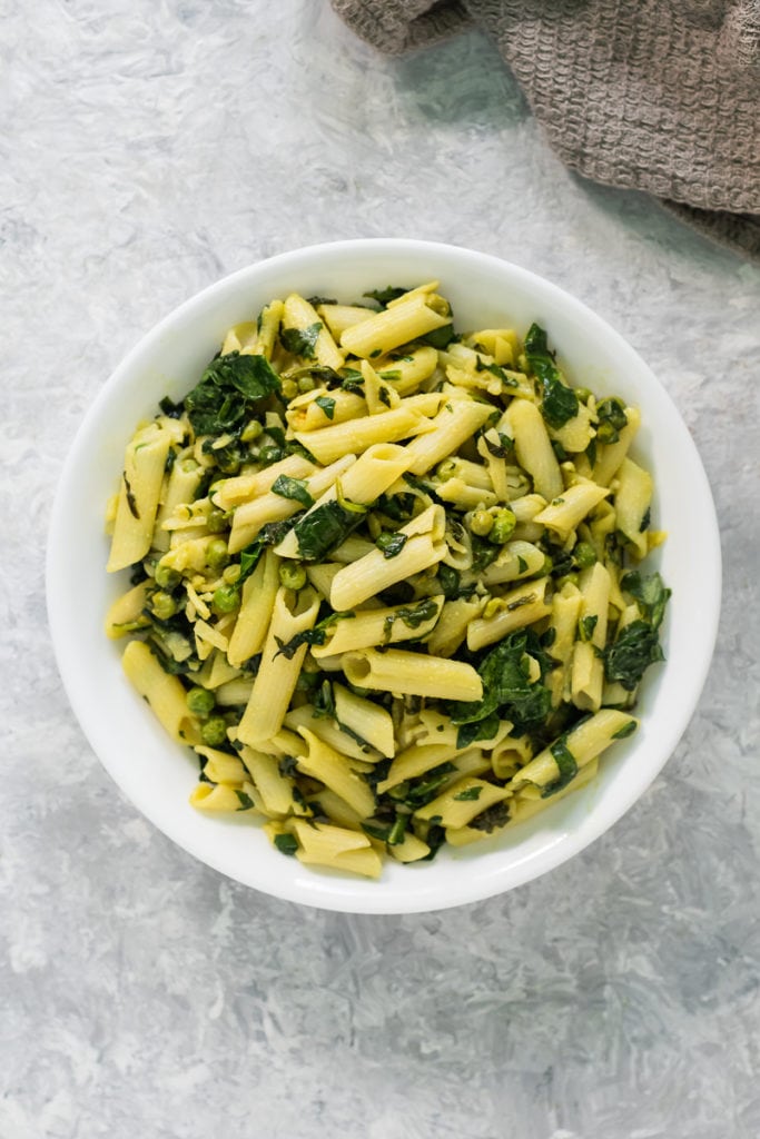 An overhead view of a heaping bowl of freshly cooked vegan spinach pasta.