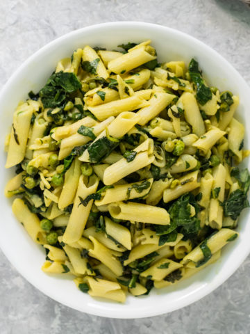 An overhead view of a heaping bowl of freshly cooked vegan spinach pasta.
