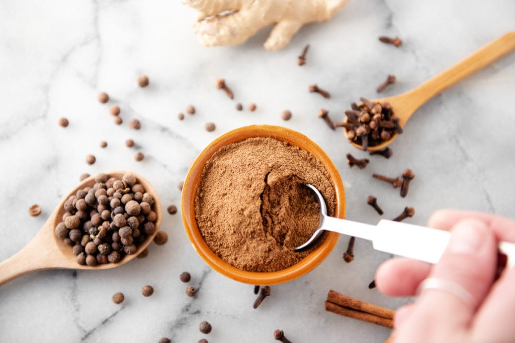 Homemade Pumpkin Pie Spice being scooped out of a bowl by a teaspoon.