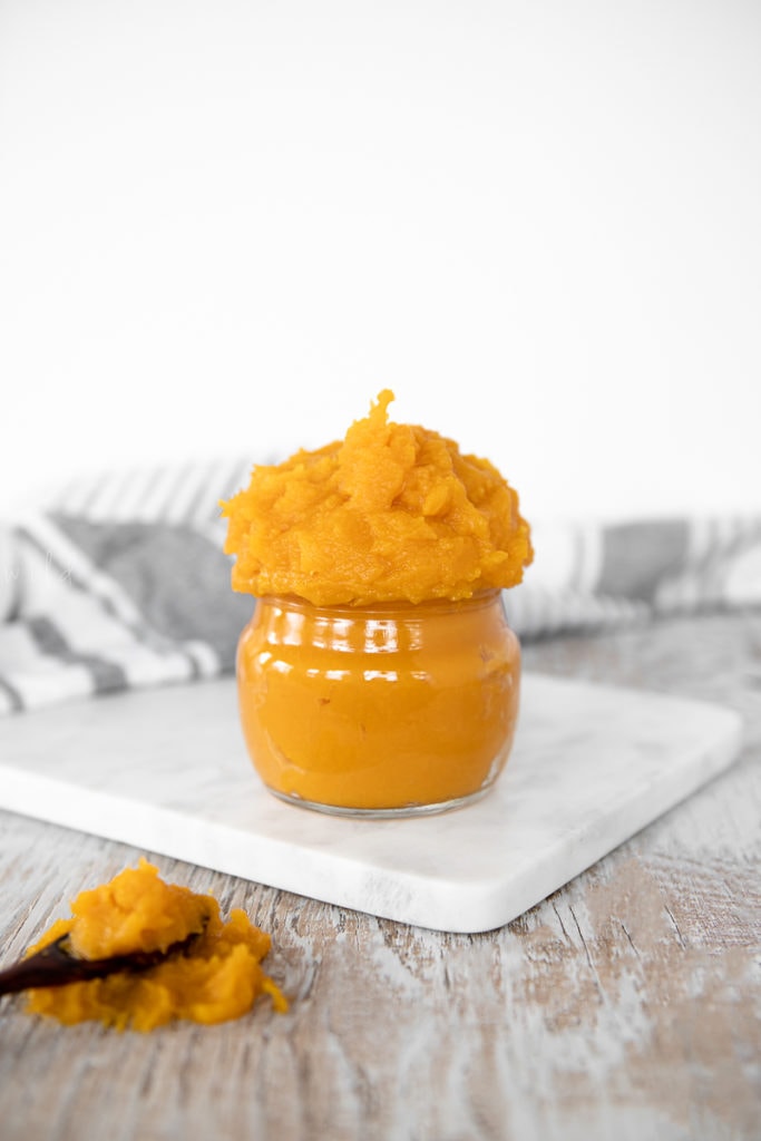 A heaping mound of homemade pumpkin purée in a glass jar.