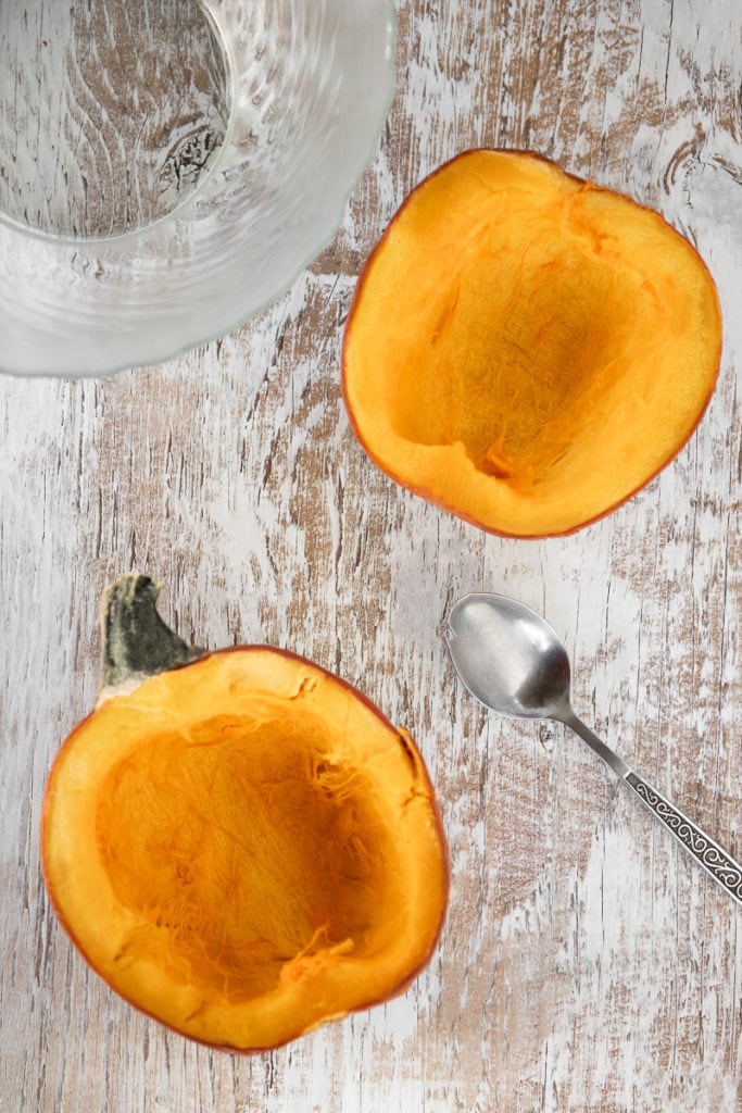 A raw pumpkin cut in half with the guts and seeds scooped out.