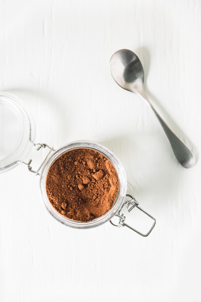 An open jar filled with Homemade French Vanilla Cappuccino Mix, and a spoon to the side