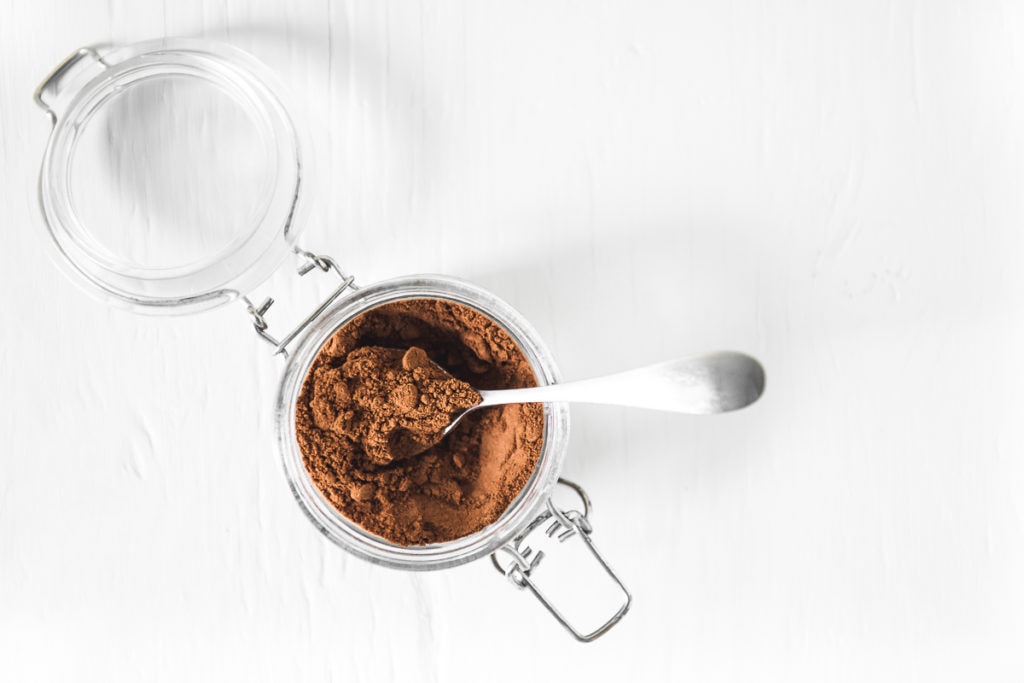 An open latch-lid jar full of Instant French Vanilla Cappuccino Mix with a spoon.