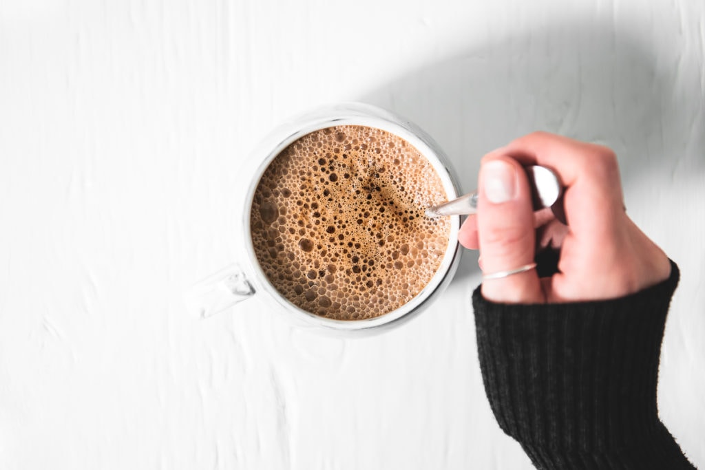 A frothy, dairy-free Homemade French Vanilla Cappuccino being stirred in a mug.