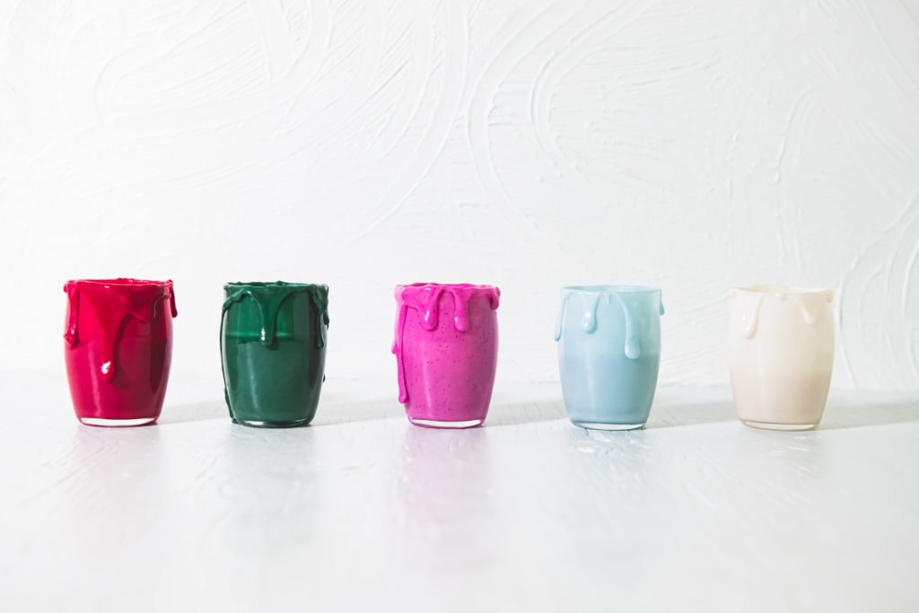 A row of five jars filled with homemade, naturally coloured icing (red, green, pink, frosty blue and white)