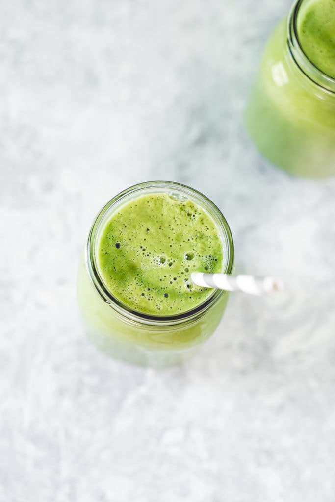 a birds-eye-view of a delicious avocado, moringa and greens smoothie a straw sticking out the front-right, ready for slurping!