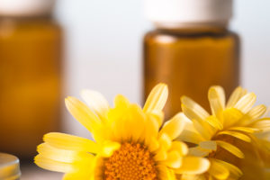 Essential Oil Bottles sitting behind fresh yellow calendula flowers