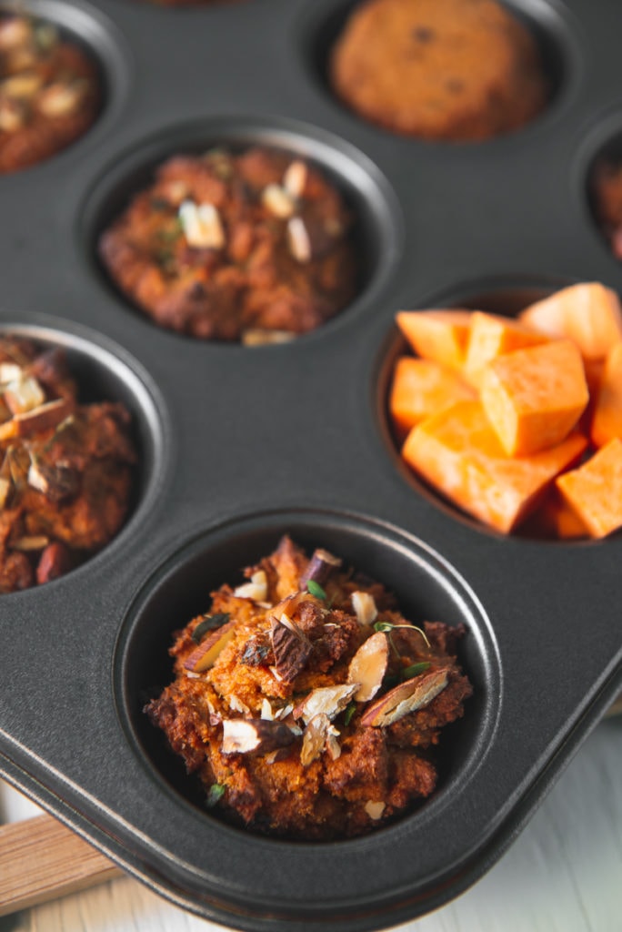 A muffin tin full of freshly baked sweet potato muffins and cubed sweet potato.