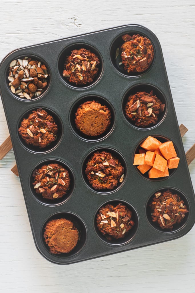 A muffin tin filled with Almond Thyme Sweet Potato Muffins, cubed sweet potato and chopped almonds.